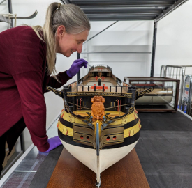 A scale-model of HMS Victory is examined by Principal Curator Victoria Ingles