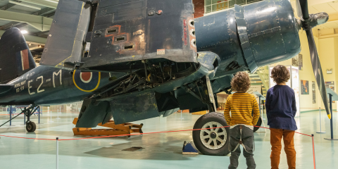 2 boys looking at an propeller airplane