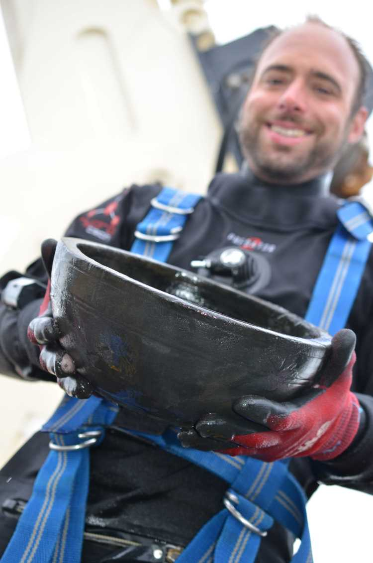 Archaeologist holding bowl from HMS Invincible