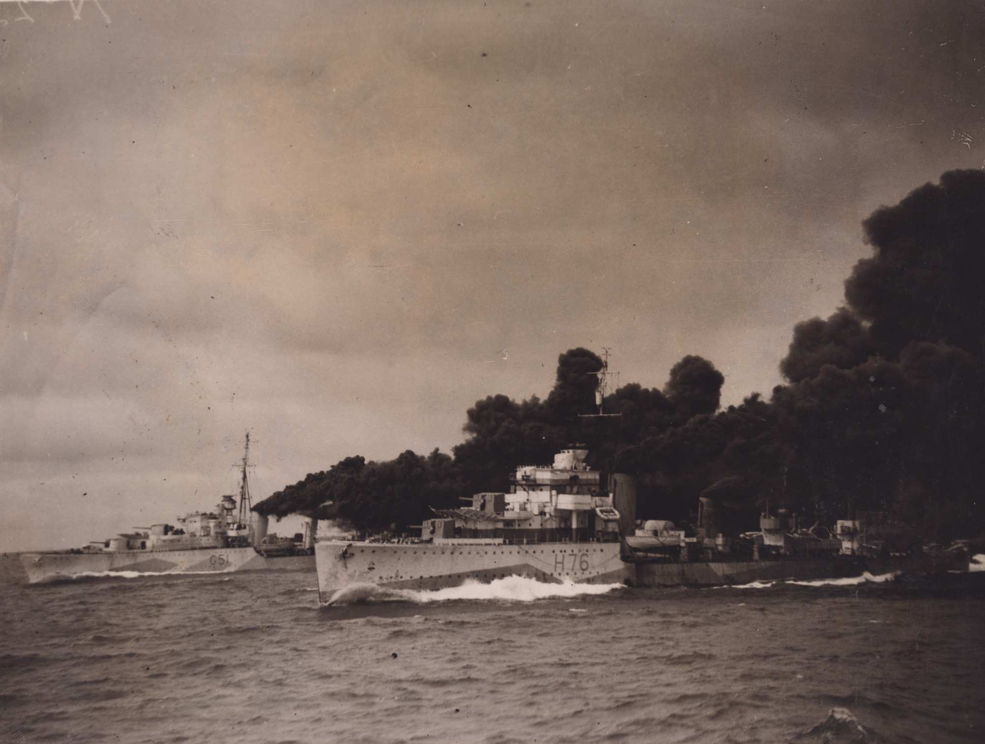 HMS Tintagel (left) and HMS Fury (right) laying a smoke screen. Credit NMRN