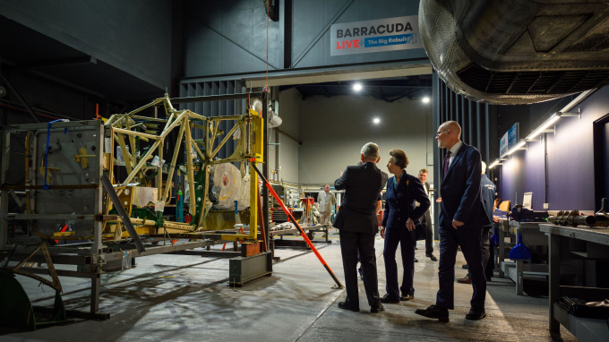 Three figures look on at the ongoing work to rebuild a Fairey Barracuda