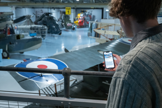 Visitor overlooking collections holding phone