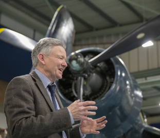 Man speaking in front of blue plane