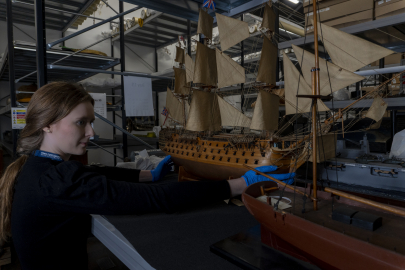 Curator holds model ship