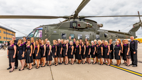 Choir standing in front of green Merlin Helicopter