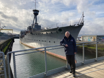 John Taylor, who served onboard HMS Caroline as an engineer, pictured infront of the ship