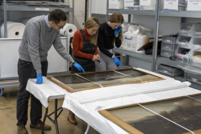 Three curators from the National Museum of the Royal Navy look over some fine art from the collection