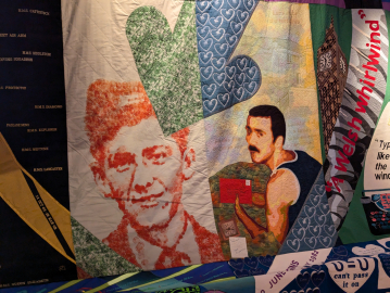 A close-up on a colourful quilt featuring images of the same man at two different ages