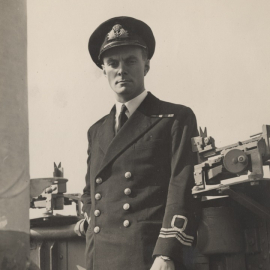 A black and white photo of a man in Royal Navy uniform next to machinery