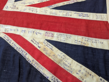 A close-up of a Union Jack flag with many names written on it