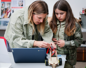 Lady and girl, working at a laptop to build a toy vehicle