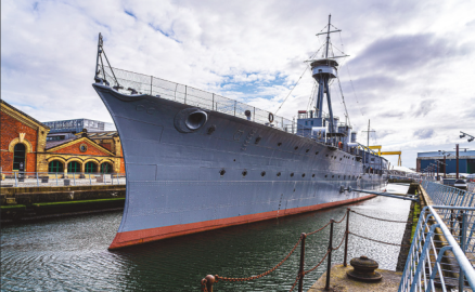 HMS Caroline shown in dock under a cloudy sky