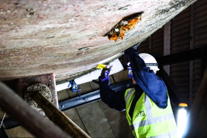 woman boatbuilder working on hull of ship