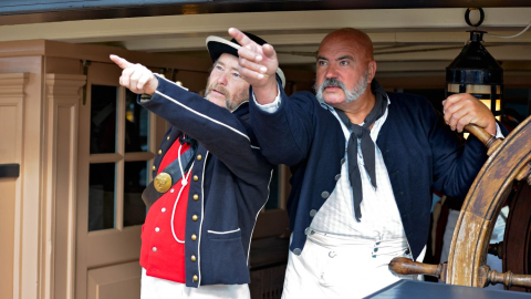 2 costume actors pointing into the distance onboard HMS Warrior