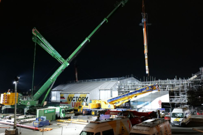 A night image of HMS Victory Mast being removed using a big green crane