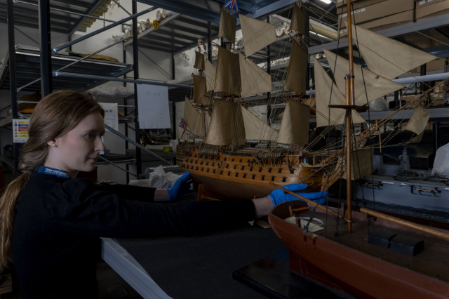 Curator holding model ship