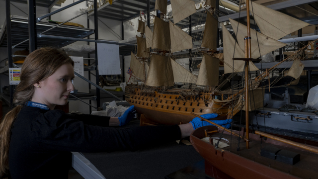 Curator holds model ship