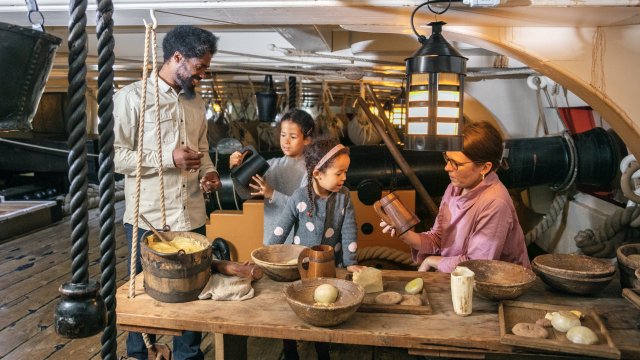 Family sitting at mess table inside HMS Victory