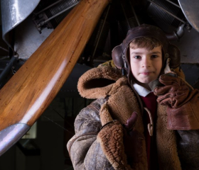 A young boy is dressed as a First World War pilot. 