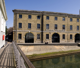 The front of a large historic building with a sign that says 'Action Stations'