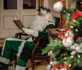 Santa sat by a tree reading a book