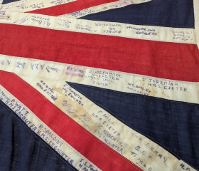 A close-up of a Union Jack flag with many names written on it