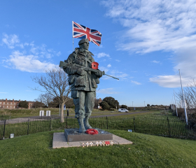A large bronze statue of a Royal Marine with a Union Jack coming out of his backpack