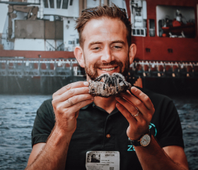 A man holding up a tarantula on a piece of wood.