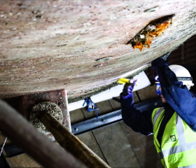 woman boatbuilder working on hull of ship