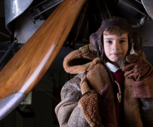 A young boy is dressed as a First World War pilot. 