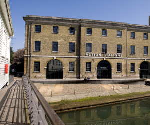 The front of a large historic building with a sign that says 'Action Stations'