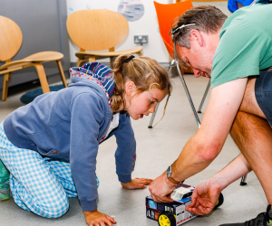 father and daughter creating battery powered vehicle out of a cardboard box
