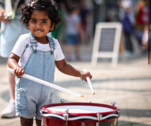 small child stood playing a drum