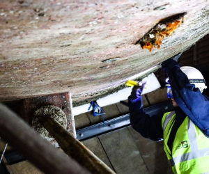 woman boatbuilder working on hull of ship