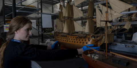 Curator holds model ship